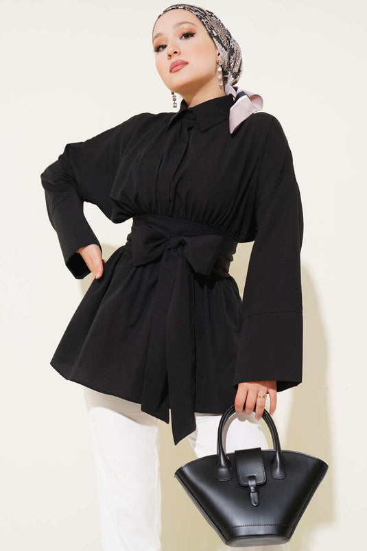 Tunique noire à ceinture intégrée et froncée sur le devant.