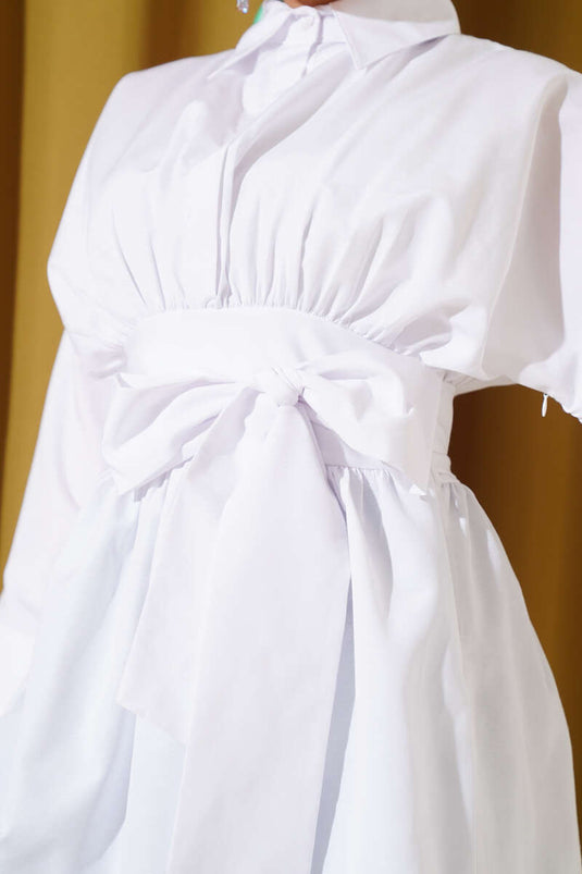 Tunique blanche à ceinture intégrée et froncée sur le devant.