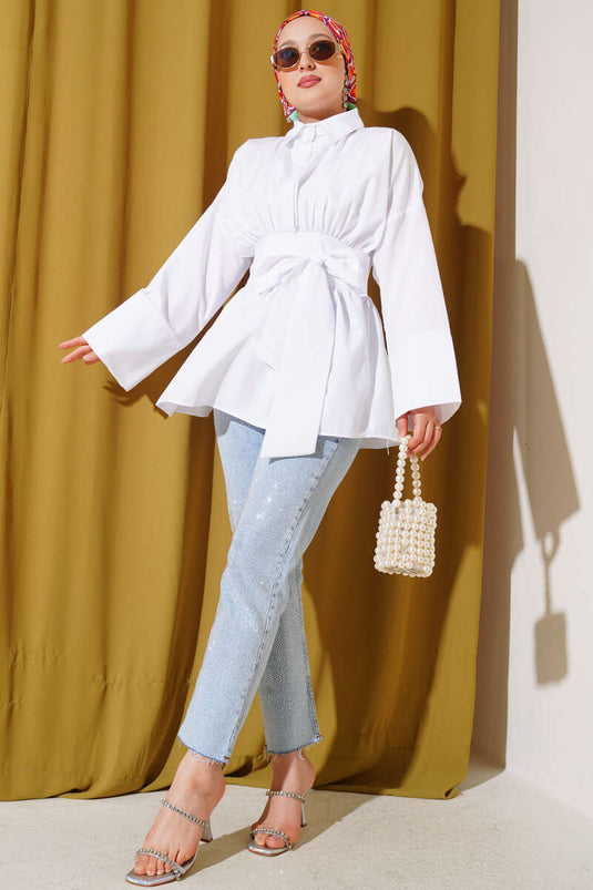 Tunique blanche à ceinture intégrée et froncée sur le devant.