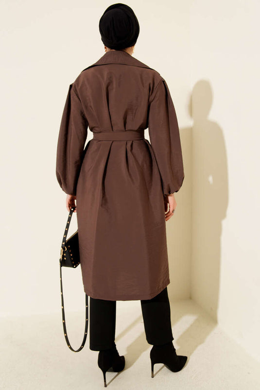 Trench-coat marron à double boutonnage, manches bouffantes et ceinture.