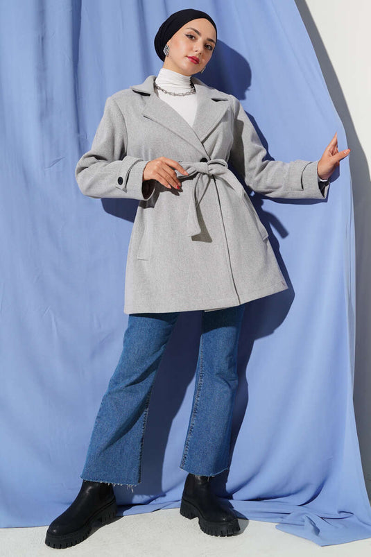 معطف قصير من الكشمير، رمادي اللون، بياقة مزدوجة الصدر وتفاصيل حزام.