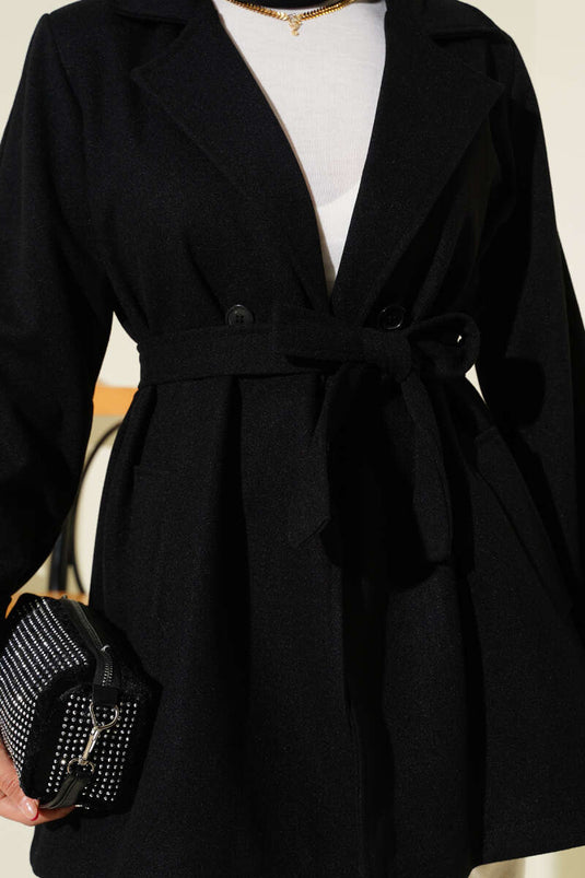 معطف قصير من الكشمير، أسود اللون، بياقة مزدوجة الصدر وتفاصيل حزام.