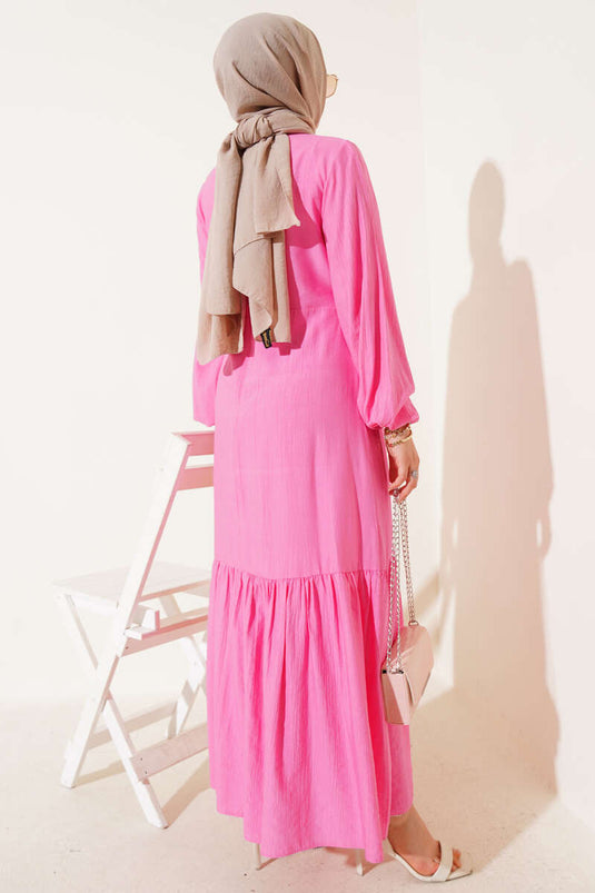 فستان وردي بربطة عنق وتفاصيل فتحات