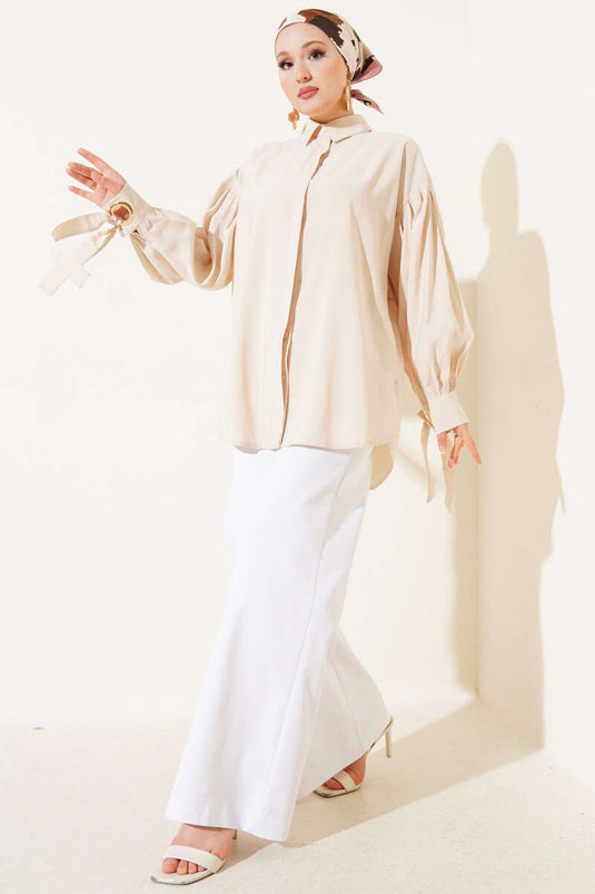 قميص بأكمام منفوخة وتفاصيل فتحات صغيرة باللون البيج