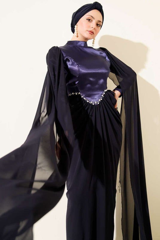 Marineblauwe avondjurk met schoudercape en details van steentjes.