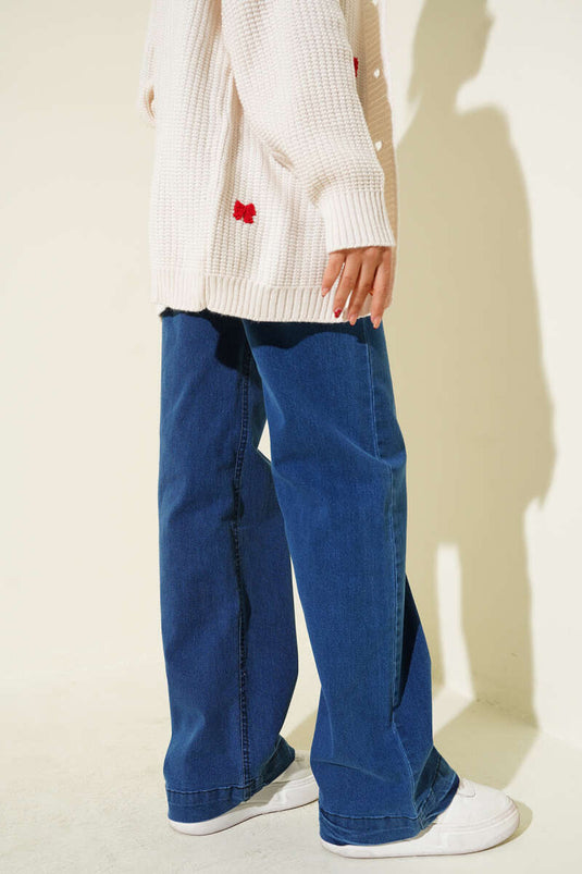 Jean en denim bleu à jambes larges avec boutons métalliques sur le devant.