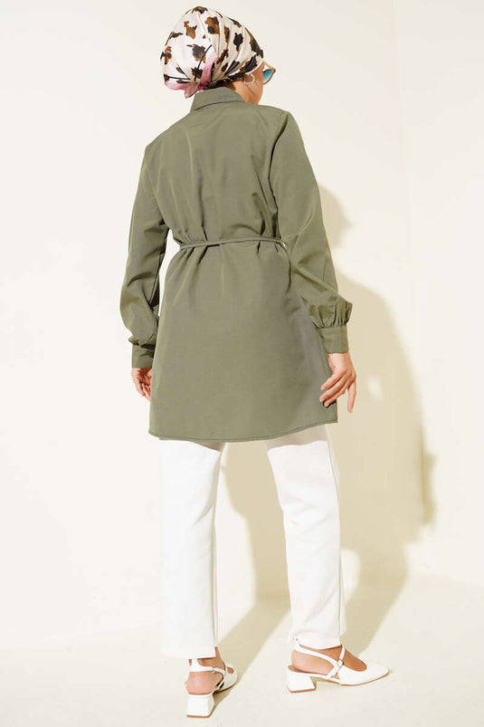سترة طويلة بفتحة أمامية عميقة وحزام برباط، لونها كاكي.