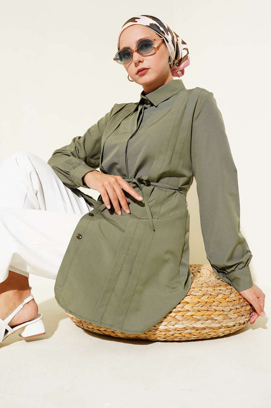 سترة طويلة بفتحة أمامية عميقة وحزام برباط، لونها كاكي.