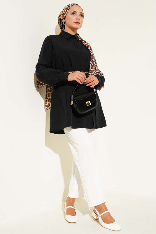 سترة طويلة بفتحة صدر واسعة وحزام برباط، لونها أسود.