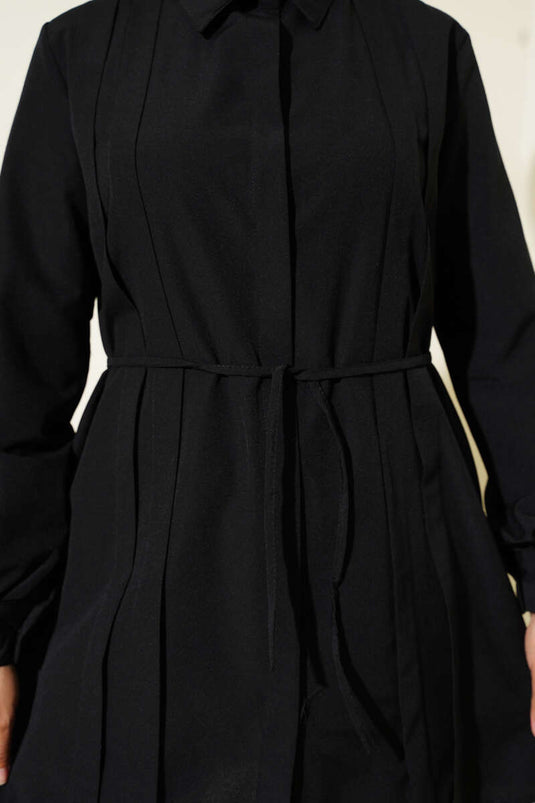 سترة طويلة بفتحة صدر واسعة وحزام برباط، لونها أسود.