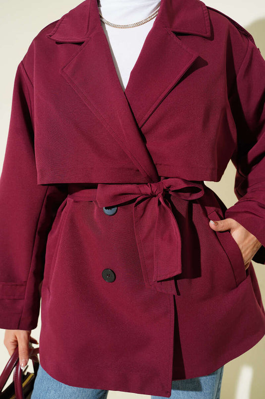 Trench-coat court bordeaux avec cape et ceinture.