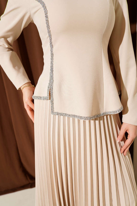 بدلة من قطعتين بتفاصيل حجرية وتنورة مطوية باللون البيج