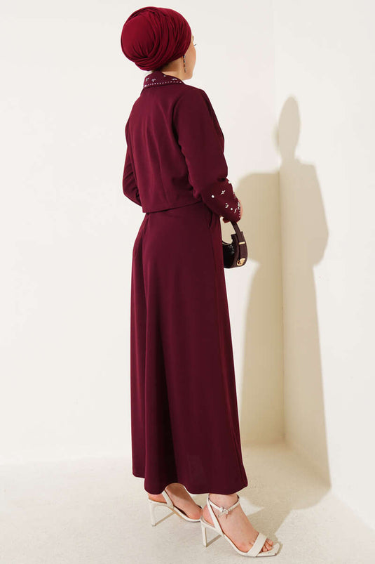 Tweedelig setje met versierde kraag, mouwen en rok in bordeauxrood.