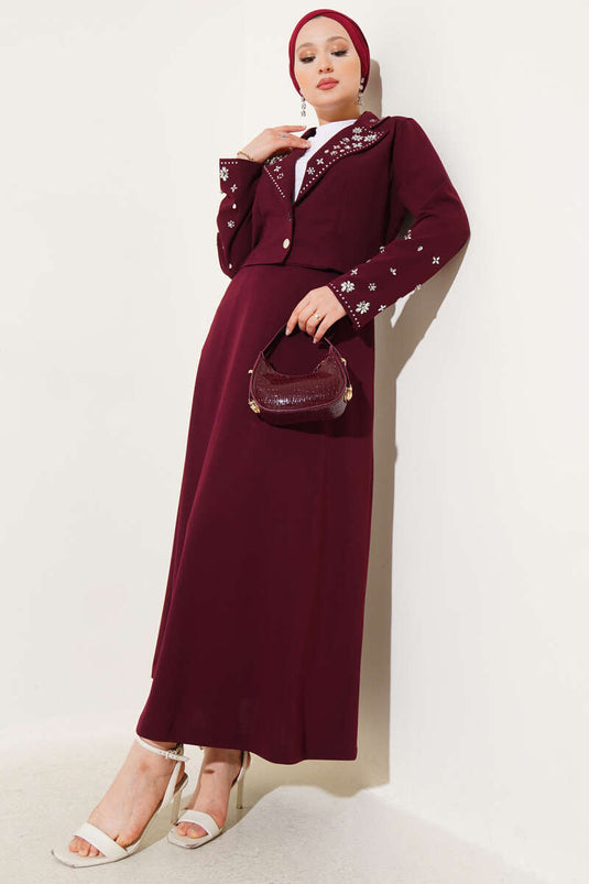 Tweedelig setje met versierde kraag, mouwen en rok in bordeauxrood.