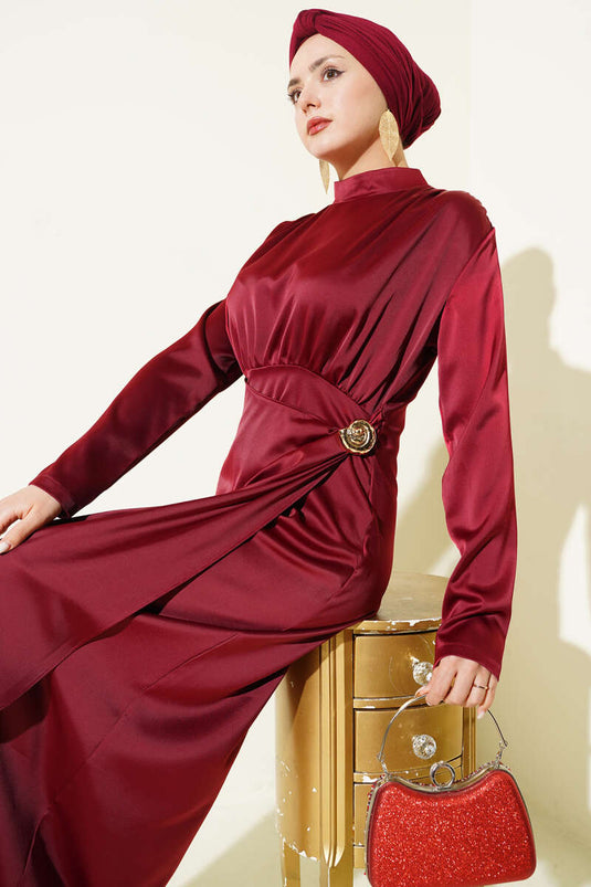 فستان سهرة ساتان عنابي مزين بطيات ذهبية ومشبك ذهبي