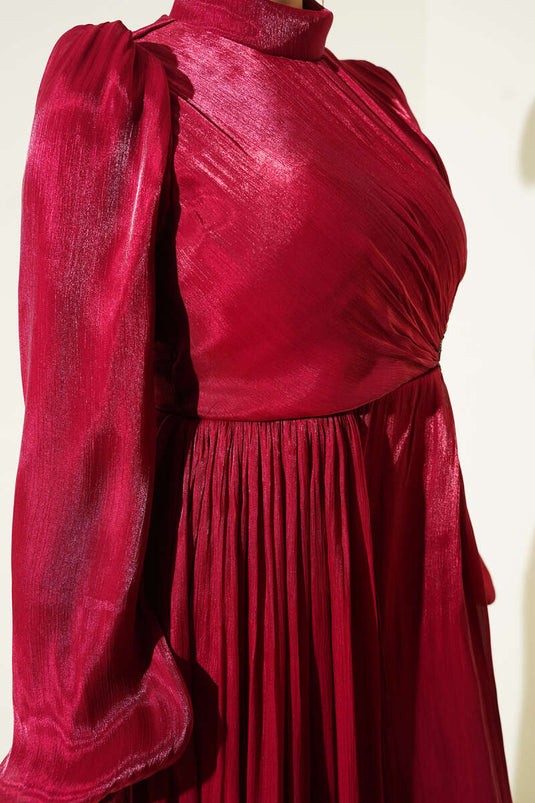 فستان سهرة عنابي بتفاصيل حجرية وتجمّع عند الخصر