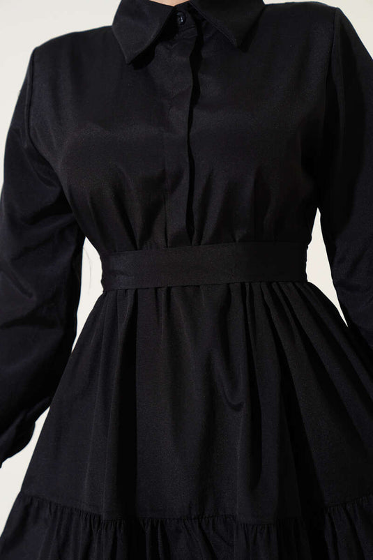 Schwarzes, halbgeknöpftes, tailliertes Lagenkleid mit Gürtel.